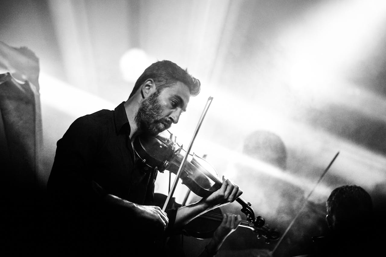 Artistic black and white photo of a male violinist playing passionately during a live performance.