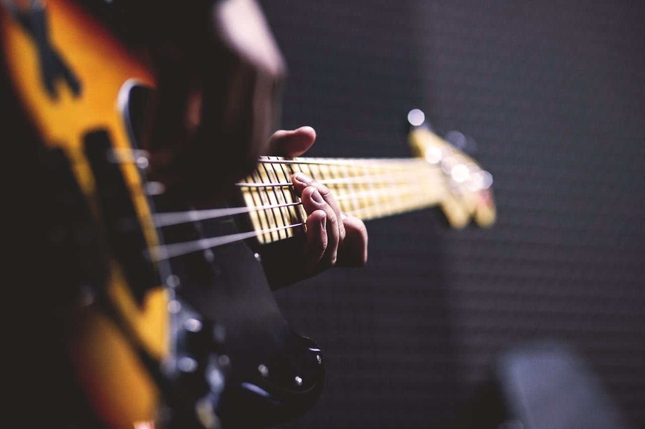 Close-up of a musician strumming an electric bass guitar with focus on fingers.
